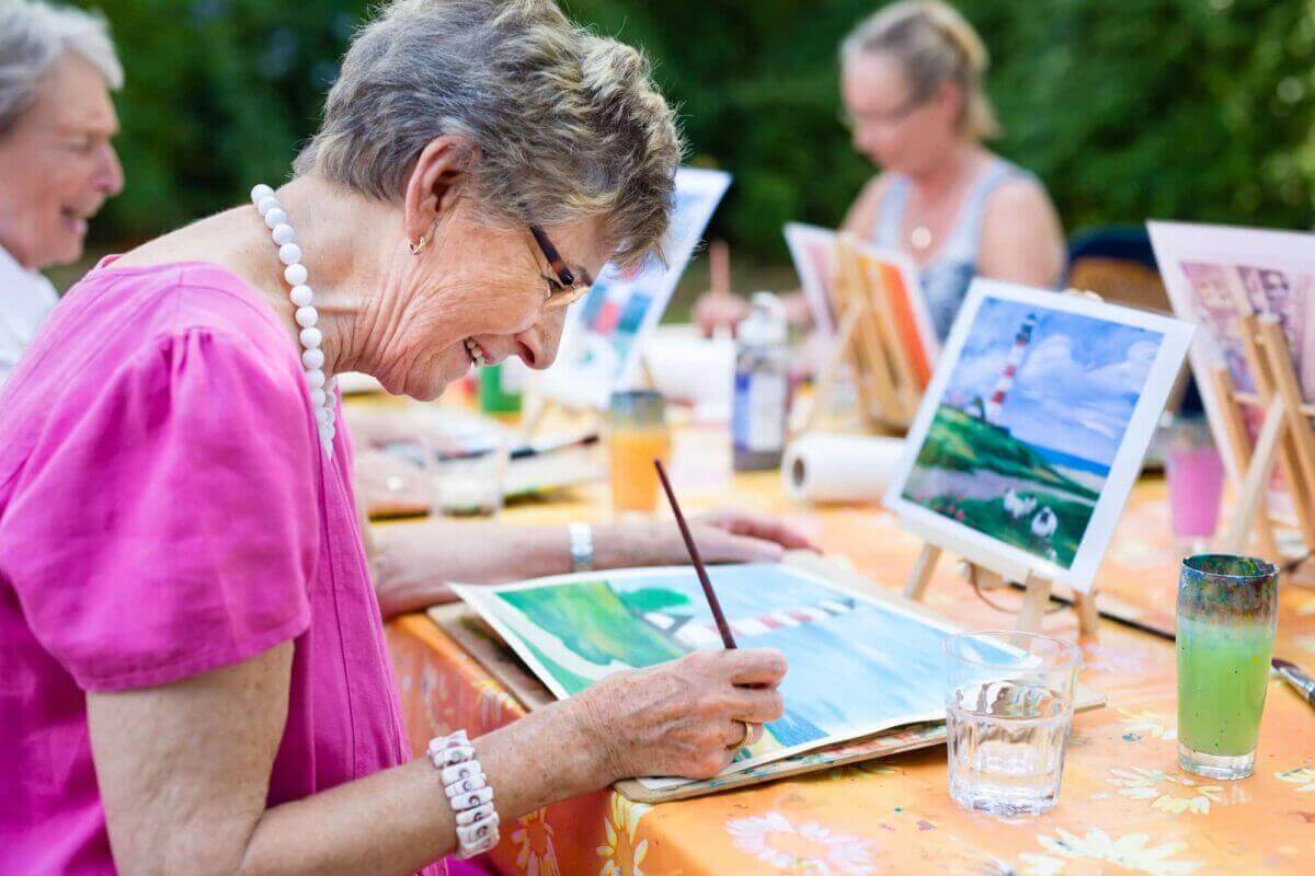 senior woman smiling while painting with the group